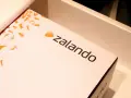 Pudełko z logo Zalando, ozdobione pomarańczowymi sylwetkami butów. Ciesz się zakupami z zalando lounge darmowa dostawa!
