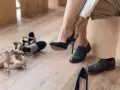 Kobieta przymierza granatowe szpilki. Obok leżą inne buty, w tym eleganckie oksfordki. Czy 13 cm jaki to rozmiar buta?