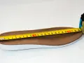 Miarka krawiecka mierzy brązową wkładkę. Długość wkładki wynosi około 23 cm, co odpowiada rozmiarowi 38.