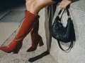 Kobieta w czerwonych kozakach i pikowanej torebce z logo Nine West. Nine West to znana marka obuwia i akcesoriów.