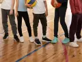Dzieci na sali gimnastycznej, zastanawiające się, jakie buty na WF do szkoły wybrać. Różne modele sportowego obuwia na drewnianej podłodze.