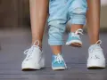 Małe niebieskie buciki dziecka i białe trampki mamy. 17 cm jaki to rozmiar buta?