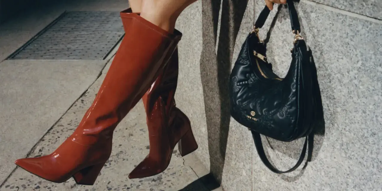 Kobieta w czerwonych kozakach i pikowanej torebce z logo Nine West. Nine West to znana marka obuwia i akcesoriów.