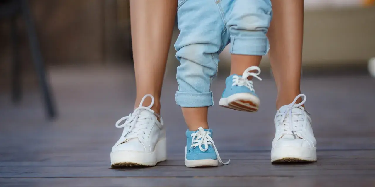 Małe niebieskie buciki dziecka i białe trampki mamy. 17 cm jaki to rozmiar buta?