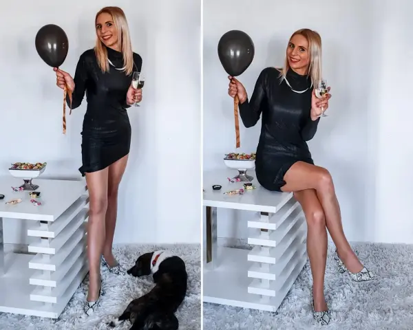 Elegancka czarna sukienka, idealna na 18. Urodziny. W dłoni czarny balon i kieliszek szampana. Na podłodze piesek.