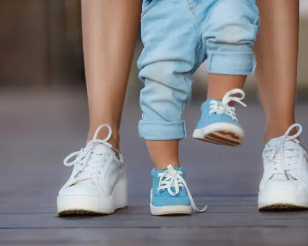 Małe niebieskie buciki dziecka i białe trampki mamy. 17 cm jaki to rozmiar buta?